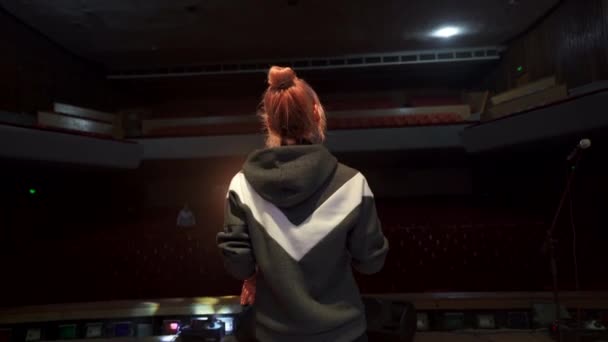 Vista trasera de la cantante cantando y bailando en el gran escenario de la sala de conciertos con auditorio vacío — Vídeo de stock