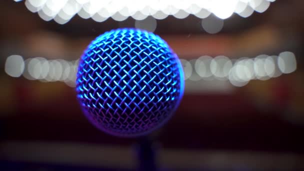 Tutup Pemandangan mikrofon di atas panggung menghadap auditorium kosong di aula konser besar. Lampu sorot berwarna — Stok Video