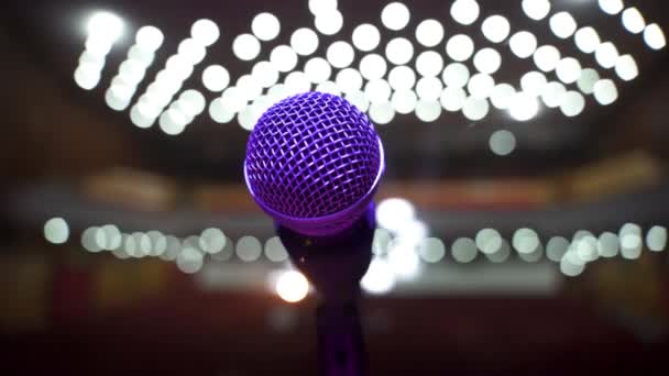 Detail Pohled na mikrofon na jevišti obrácený k prázdnému hledišti ve velkém koncertním sále. Barevné reflektory — Stock video
