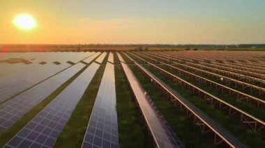 Parlak günbatımında güneş çiftliğindeki büyük güneş panellerine hava aracı görüntüsü. Güneş pili santralleri. HDR video 4k.