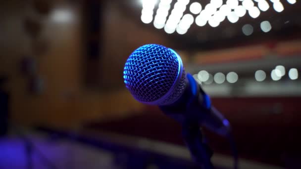 Close up Zicht op microfoon op podium tegenover leeg auditorium in grote concertzaal. Kleurrijke spots — Stockvideo