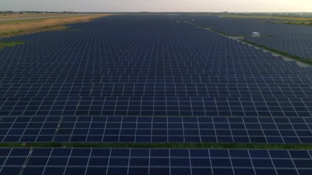 Za slunečného letního večera létá dron nad velkými solárními panely na solární farmě. Solární elektrárny, zelená tráva. Video - záběry 4k. — Stock video