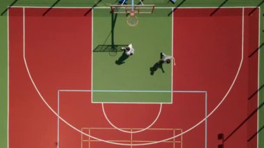 Aerial view of two young male friends playing basketball on court outdoors.