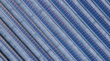 Kışın erken saatlerinde güneş batımında güneş çiftliğindeki büyük güneş panellerinin insansız hava aracı görüntüsü. Güneş pili santralleri