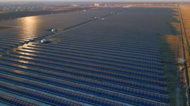 Kışın erken saatlerinde güneş batımında güneş çiftliğindeki büyük güneş panellerinin insansız hava aracı görüntüsü. Güneş pili santralleri
