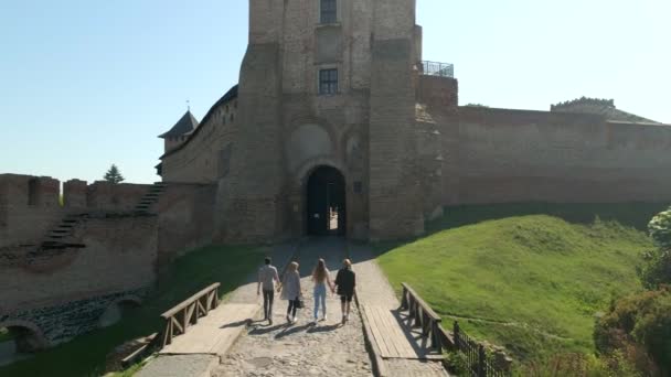 O drone voa sobre o grupo de amigos novos que andam ao castelo medieval pequeno na cidade européia pequena no dia ensolarado do verão, tiro lento do movimento — Vídeo de Stock