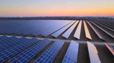 Kışın erken saatlerinde güneş batımında güneş çiftliğindeki büyük güneş panellerinin insansız hava aracı görüntüsü. Güneş pili santralleri
