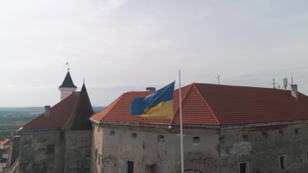 Bandera de Ucrania ondea en la pared de un antiguo castillo medieval en la pequeña ciudad europea — Vídeo de stock