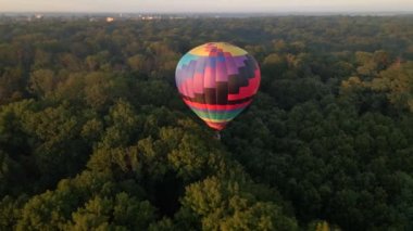 Ukrayna 'nın Kiev bölgesinde yaz gündoğumunda küçük Avrupa şehrinde yeşil parkın üzerinde uçan renkli sıcak hava balonlarının insansız hava aracı görüntüsü