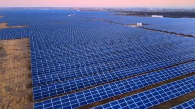 Kışın erken saatlerinde güneş batımında güneş çiftliğindeki büyük güneş panellerinin insansız hava aracı görüntüsü. Güneş pili santralleri