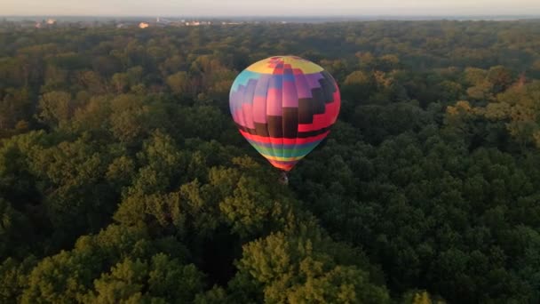 Luftaufnahme eines bunten Heißluftballons, der bei Sonnenaufgang über einem grünen Park in einer kleinen europäischen Stadt fliegt, Region Kiew, Ukraine — Stockvideo