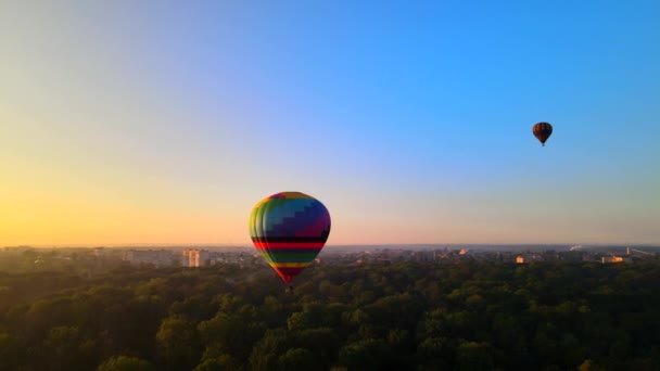 Ukrayna 'nın Kiev bölgesinde yaz günbatımında küçük Avrupa şehrinde yeşil parkın üzerinde uçan renkli sıcak hava balonunun HDR görüntüsü — Stok video