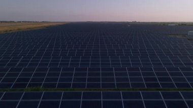 Kışın erken saatlerinde güneş batımında güneş çiftliğindeki büyük güneş panellerinin insansız hava aracı görüntüsü. Güneş pili santralleri