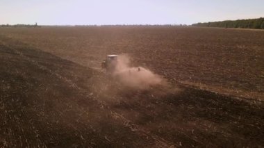 Ağır çekimde traktör tarlasının drone görüntüsü. Yerde çalışan traktörün hava görüntüsü. Mevsimlik tarım sonbahar çalışmaları.