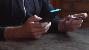Siyah kapüşonlu bir iş adamı. Kredi kartı ve akıllı telefonla online alışveriş yapıyor.