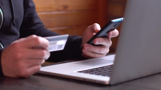 Бизнесмен в черной толстовке делает онлайн оплату с помощью кредитной карты и смартфона, онлайн покупки — стоковое видео