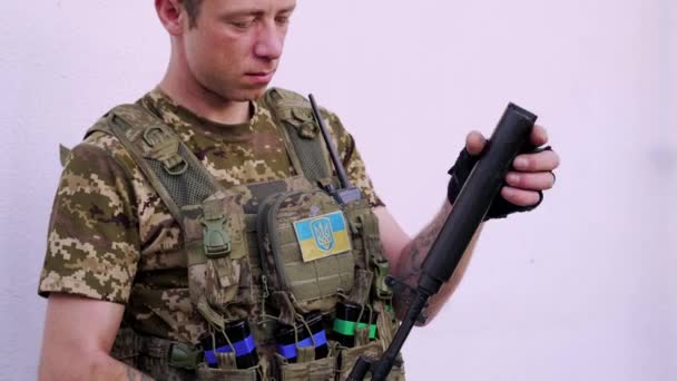 戦闘迷彩とボディアーマーのウクライナ軍の男は 彼のアサルトライフルにサイレンサーを取り付けます ウクライナでの戦争 2022年 — ストック動画