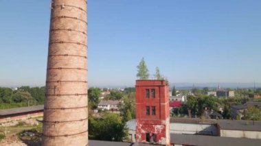 Old industrial territory. Abandoned buildings of ancient factory. Ruined edifices in summer. Old brick pipes of industry. Aerial view.