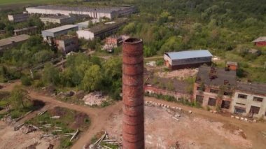 Old industrial territory. Abandoned buildings of ancient factory. Ruined edifices in summer. Old brick pipes of industry. Aerial view.