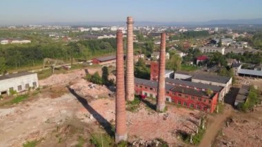 Old industrial territory. Abandoned buildings of ancient factory. Ruined edifices in summer. Old brick pipes of industry. Aerial view.