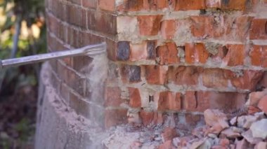 Break up, professional worker drills old brick tube with jackhammer, close up shot. Construction snd demolition concept.