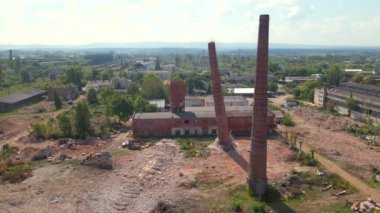Demolition of old industrial brick pipe at the factory. Destruction and lot of dust after falling. Slow motion aerial 4k shot.