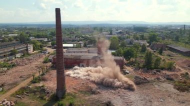 Demolition of old industrial brick pipe at the factory. Destruction and lot of dust after falling. Slow motion aerial 4k shot.