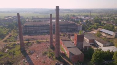 Old industrial territory. Abandoned buildings of ancient factory. Ruined edifices in summer. Old brick pipes of industry. Aerial view.