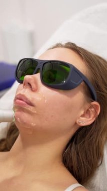 Kadın, güzellik salonunda modern İskenderiye lazer lazer temizleme prosedürüyle karşı karşıya. Kadın güzelliği, kozmetik bilimi, epilasyon kavramı. Dikey çekim.
