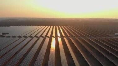 Kışın erken saatlerinde güneş batımında güneş çiftliğindeki büyük güneş panellerinin insansız hava aracı görüntüsü. Güneş pili santralleri. Renkli video 4k.