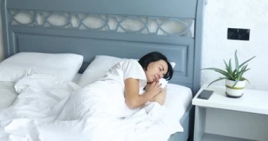 Büyük ve rahat bir yatakta tek başına uyuyan bir kadın. Öğleden sonra beyaz çarşaf, yaşam tarzı, rahat yastık, yatak.