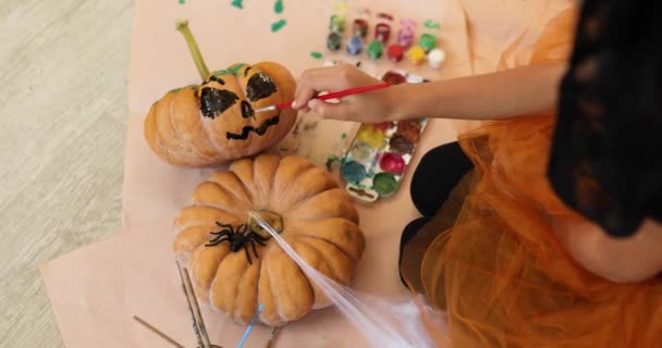 Kleines Mädchen Zeichnet Gesicht Auf Orangefarbenen Halloween Kürbis Hause — Stockvideo