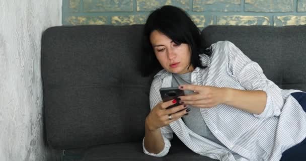 Mujer Joven Relajada Encuentra Sofá Sala Estar Mientras Mira Teléfono — Vídeo de stock