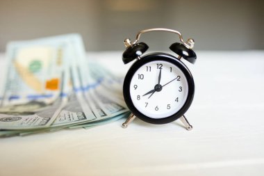 Alarm saati ve para beyaz ahşap arka planda, zaman para kavramıdır.