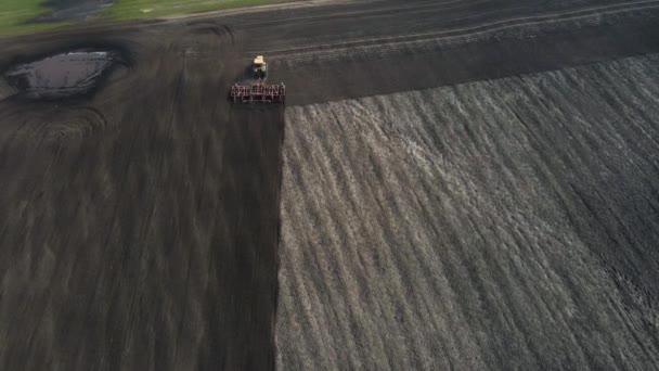 Flygfoto av en modern gul traktor plogning torr jordbruksmark, förbereda mark för sådd — Stockvideo