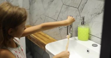 Evdeki banyoda diş fırçasıyla diş fırçalayan küçük bir kız. Sağlıklı hijyen kavramı.