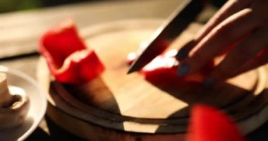 Tanınmayan bir kadın haftasonu ahşap tahtada taze biber sebzeleri kesiyor bahçede, dışarıda barbekü yapıyor, ızgaraya hazırlanıyor, yaz aile pikniğine hazırlanıyor, doğada yemek yiyor..