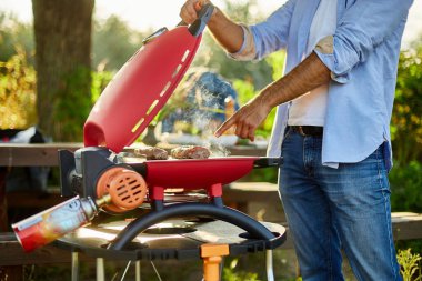 Adam gaz ızgarasında et kızarttı arka bahçede ızgara ızgara et, ızgara et, yaz aile pikniği, doğada yemek..