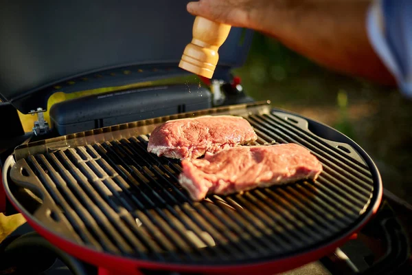 裏庭のバーベキューグリル屋外でのガスグリルで男の手の調味料の肉を閉じる 焼きローストステーキ肉 夏の家族のピクニック 自然食品 — ストック写真