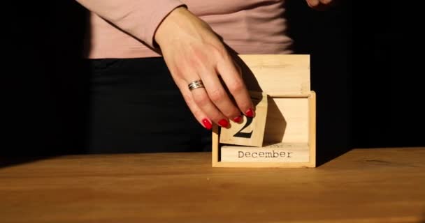 Смена женской руки, дата на деревянном календаре 25 декабря — стоковое видео