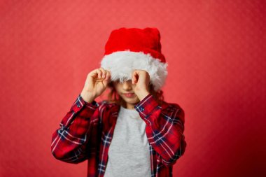 Noel Baba Şapkalı küçük kız birilerine dargın, ruh hali değişiklikleri izole edilmiş kırmızı stüdyo geçmişi