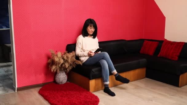 携帯電話を使用して熟女 ソファに座って スマートフォンアプリを閲覧 画面を見て シニア女性 インターネットストアでのショッピング シニア人 現代技術 — ストック動画