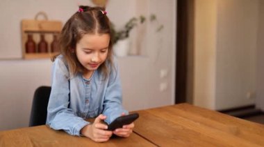 Küçük kız cep telefonuyla oyun oynuyor, anne akıllı telefonu aldı.