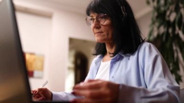 Kablosuz kulaklık takan son sınıf kadını Webinar, antrenman, kurs, dizüstü bilgisayar dersleri...