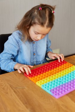 Küçük kız büyük silikon popitle oynuyor, basit gamzeler, kabarcık oyuncaklar, evde stres önleyici oyuncaklar. Akıl sağlığı oyuncağı konsepti