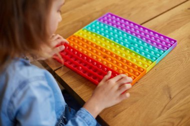 Küçük kız büyük silikon popitle oynuyor, basit gamzeler, kabarcık oyuncaklar, evde stres önleyici oyuncaklar. Akıl sağlığı oyuncağı konsepti