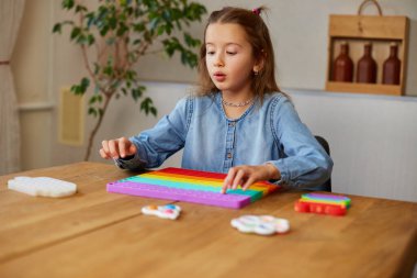 Küçük kız büyük silikon popitle oynuyor, basit gamzeler, kabarcık oyuncaklar, evde stres önleyici oyuncaklar. Akıl sağlığı oyuncağı konsepti