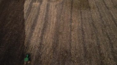 Hava manzarası, tarlada çalışan yeşil traktörün drone görüntüsü, sonbaharda büyük bir çiftlikte tarla süren traktör tarlaları. Yukarıdan tarım, Endüstri.