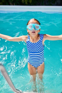 Happy Little girl in goggles having fun, dives and swim in the swimming pool, summer vacation at home, tropical holiday resort. clipart