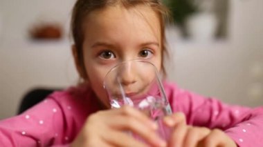 Mutfakta cam suyu içen küçük mutlu kızı kapatın, çocuk günlük temiz su, dehidrasyon, sağlıklı yaşam tarzı konsepti, Kameraya Gülümseme